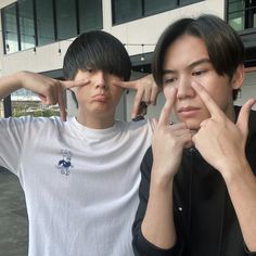 two young men standing next to each other with their fingers on their foreheads and one pointing at the camera