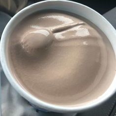 a white bowl filled with brown liquid on top of a table