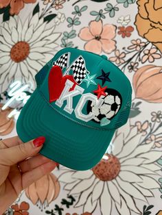 The KC Teal Soccer Ball Trucker Hat is a stylish addition to your wardrobe. Featuring a vibrant Red heart, KC, Soccer Ball makes this hat is perfect for adding a pop of color to any outfit. Made with high-quality materials, it provides both comfort and durability, making it a must-have for any fashion-forward individual. Details: Adult Size Adjustable Fit One Size Fits Most Trucker Hat Mesh Back Lightweight 100% Polyester Hat Bar, Patch Hats, Personalized Hats, Hat Ideas, 12th Birthday, Soccer Fans, Soccer Mom, Bar Ideas, Soccer Team