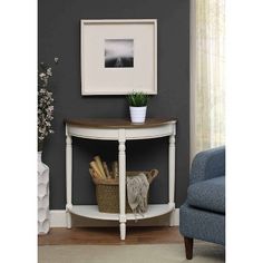 a white corner table with a basket on it and a framed photo above the shelf