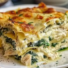 a white plate topped with lasagna covered in cheese and spinach