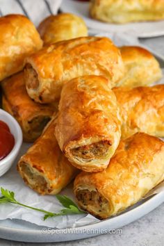 several sausage rolls on a plate with ketchup