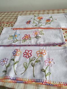 three embroidered napkins with flowers on them