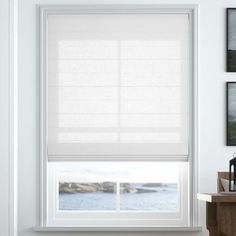 a window with white blinds in a room next to a table and pictures on the wall