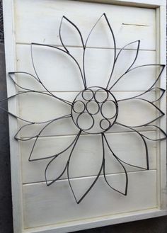 a metal sunflower is mounted on a white wood paneled wall in the shape of a flower