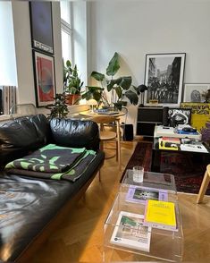 a living room filled with black leather furniture and lots of books on top of a wooden floor