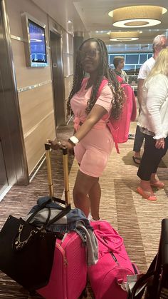 a woman in pink is standing with her luggage at the airport and smiling for the camera