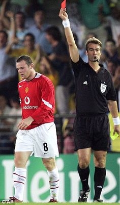 a man holding up a red card in front of a crowd at a soccer game