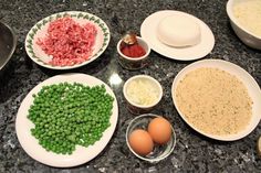 an assortment of food is displayed on the counter top, including eggs, meat and vegetables