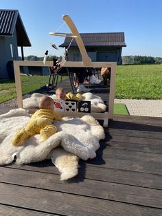 a baby laying on top of a wooden floor next to a white teddy bear chair