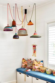 a room filled with lots of hanging lights and baskets on top of a blue bench