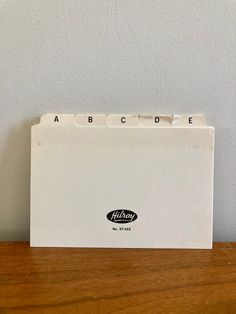 an empty file folder sitting on top of a wooden table next to a white wall