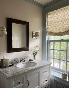 a bathroom with a sink, mirror and window covered in shades on the windowsill