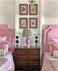 two pink beds in a room with pictures on the wall above them and a chest of drawers