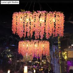 the chandelier is decorated with pink flowers and hanging from it's ceiling