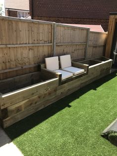 a wooden bench sitting on top of a green grass covered field next to a fence