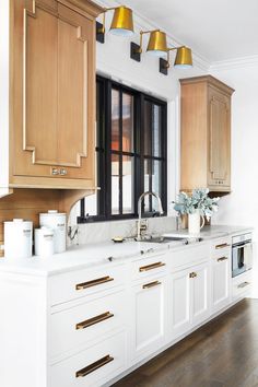 a kitchen with wooden cabinets and white counter tops next to a window that has black framed windows