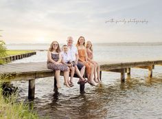 a family sitting on a dock at the water's edge