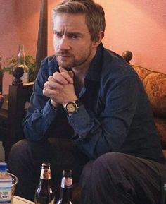 a man sitting on top of a couch next to two beer bottles