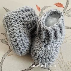 a pair of crocheted baby shoes sitting on top of a bed