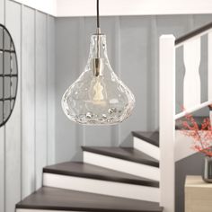 a glass light fixture hanging from the ceiling in a room with stairs and railings