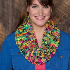 a smiling woman wearing a multicolored knitted cowgirl neck scarf over her face