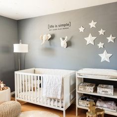 a baby's room with white crib and stars on the wall above it