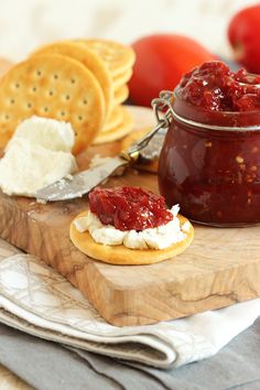 there is a jar of jam and crackers next to it on a cutting board