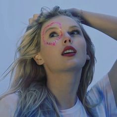 a woman with her face painted pink and holding her hair in front of her head