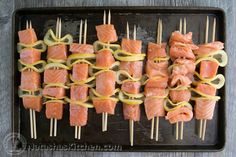 several skewered salmons are on a black tray