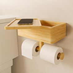 two rolls of toilet paper are hanging on the wall next to a wooden tray with a cell phone