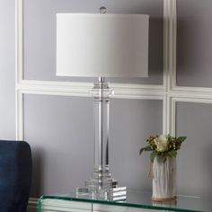 a glass table with a lamp on it and a blue chair in front of the wall