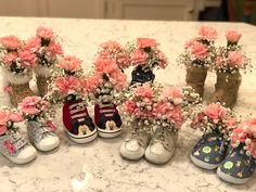 several pairs of baby's shoes with flowers in them sitting on a counter top