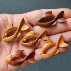 small wooden objects in the palm of someone's hand, some are shaped like fish