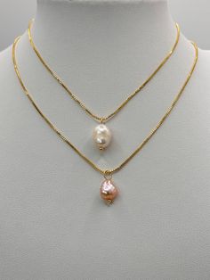 Presented here are two  gold necklace sold separately , each featuring a single baroque pearl pendant.  The  necklace length is adjustable with a sliding bead. The top chain holds a classic white pearl with a soft luster, while the second chain displays a pearl with a pinkish hue, giving off a gentle iridescence.  The baroque pearls, with their unique shapes, provide a natural and organic elegance to the otherwise sleek and simple gold plated chains. Both necklaces combine the timeless appeal of Gold Double Strand Necklace With Pearl Pendant, Gold Double Strand Pearl Necklace With Adjustable Chain, White Pearl Pendant Drop Necklace, Gold Double Strand Pearl Necklace With Pendant, Gold Pear-shaped Single Strand Pearl Necklace, Adjustable Pearl Drop Necklace With Pearl Pendant, White Adjustable Drop Necklace With Pearl Pendant, Adjustable White Drop Necklace With Pearl Pendant, Gold Drop Necklace With Baroque Pearl As A Gift