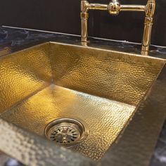 a gold sink in a bathroom with black walls