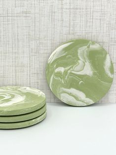 three green plates sitting on top of a white counter next to a wallpapered background