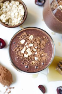 chocolate smoothie with nuts and cranberries in two cups on a white surface