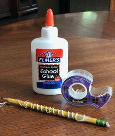 a wooden table with some school supplies and a glue bottle on top of the table