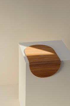 a wooden object sitting on top of a white box next to a light brown wall