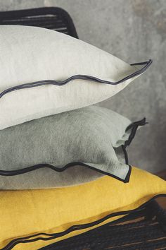 three pillows stacked on top of each other in front of a gray and yellow wall