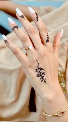 a woman's hand with tattoos on it and her nails in black ink,