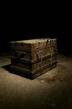 an old trunk sitting in the middle of a dark room with no one around it