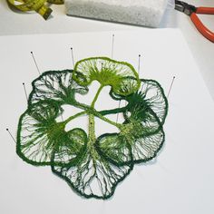 a piece of art that is made out of yarn and thread with scissors next to it