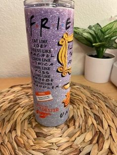 a purple glitter tumbler sitting on top of a table next to a potted plant