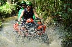 two people riding an atv through the water