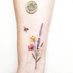 a small flower tattoo on the ankle with a butterfly and bee flying over it's back