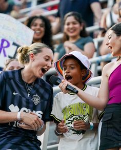 two girls singing into a microphone at a sporting event