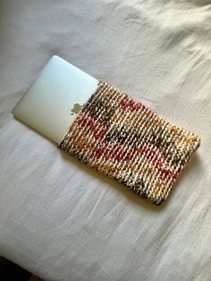 an apple laptop computer sitting on top of a white bed covered in blankets and pillows