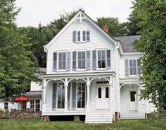 a large white house sitting in the middle of a lush green field next to trees